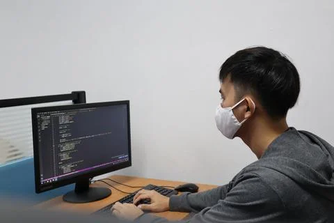 Young boy in a mask learning coding on his computer during the pandemic Foto stock