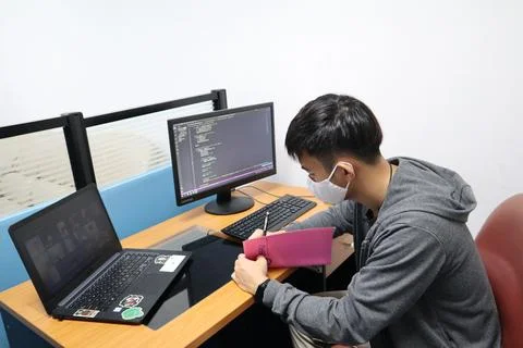 Young boy in a mask learning coding on his computer during the pandemic 写真素材