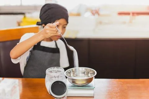 Young boy measuring ingredient for baking in kitchen. Stock Illustration