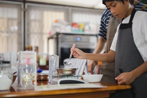 Young boy measuring ingredient for baking in kitchen. Stock Illustration