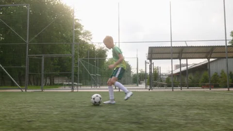 A young boy in motion during a soccer practice on an outdoor field. He is Stock Footage 284181720
