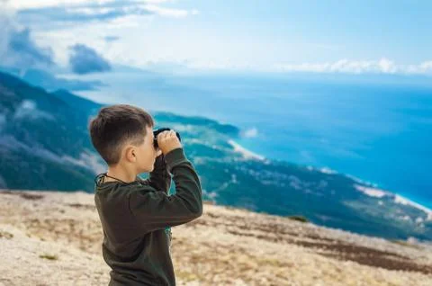 Young boy at mountain top looking through binoculars Stock Photos