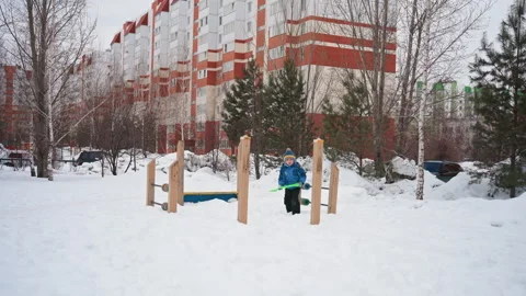 Young boy navigates winter playground obstacles alone. Young child engaging with Stock Footage 334718076