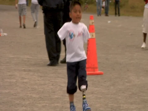 A young boy with no arms and one leg and a prosthetic leg finishing a race Stock Footage 90361483