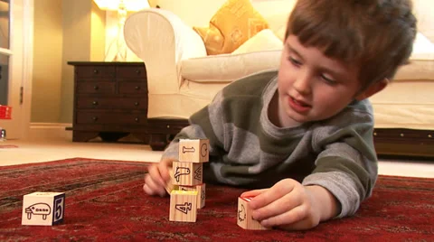 A young boy no older than 4 years old stacks play bricks until they collapse. Vídeos de archivo 32961719