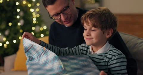 A young boy opens a gift from Santa Claus, enjoys the gift tears the colored Stockbeeldmateriaal 210442899