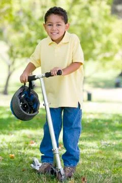 Young boy outdoors on scooter smiling Stock Photos