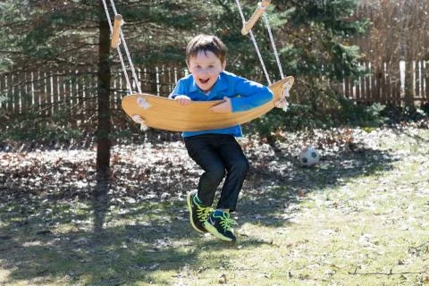 Young boy outside in backyard having fun on a swing Stock Photos
