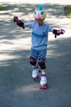 Young boy outside learning to riding on roller skates on driveway wearing Stock Photos