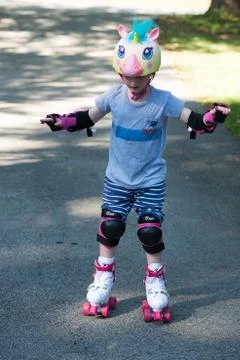 Young boy outside learning to riding on roller skates on driveway wearing Stock Photos