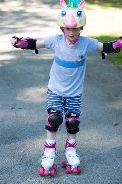 Young boy outside learning to riding on roller skates on driveway wearing Stock Photos