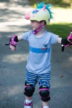 Young boy outside learning to riding on roller skates on driveway wearing Stock Photos