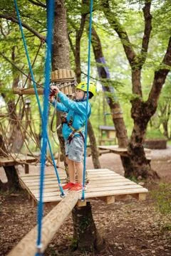 Young boy passing cable route among trees, extreme sport in adventure park Foto stock