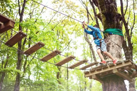 Young boy passing cable route among trees, extreme sport in adventure park Foto stock