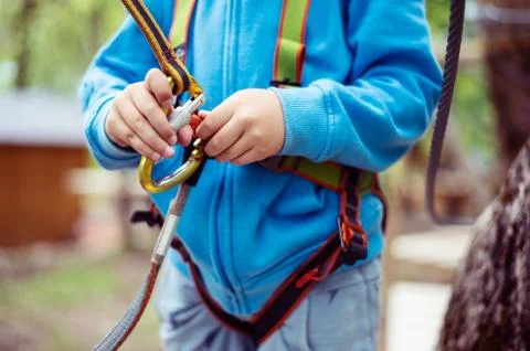 Young boy passing cable route among trees, extreme sport in adventure park Stock Photos