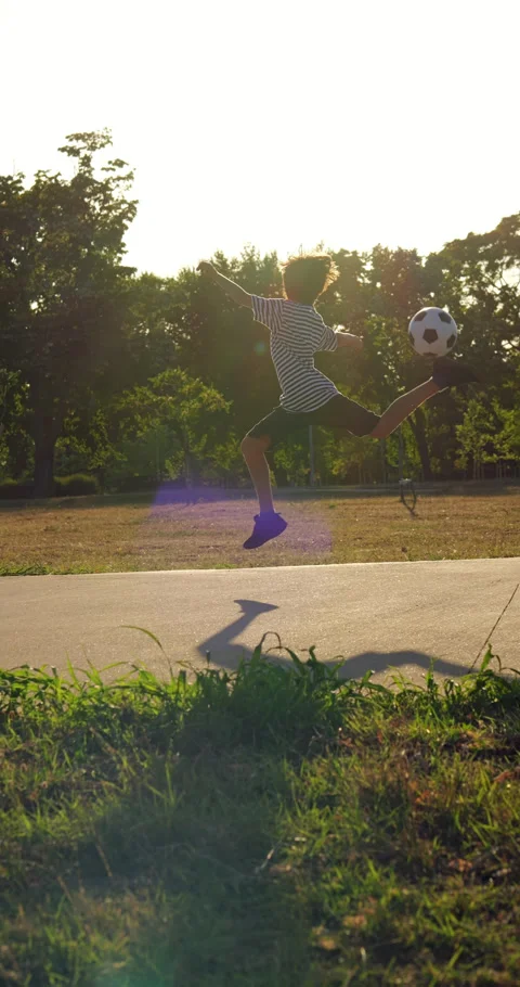 Young boy performing rainbow flick trick with ball in park, slow motion shot 库存影片 344728429