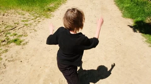 A young boy performs a dramatic dance on a sunny day, showcasing his expressive Stock Footage 278057417