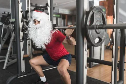 Young boy performs squats on legs training with Santa Claus costume ready to  Stock Photos