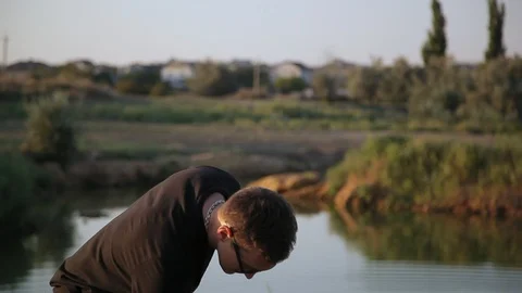 Young boy picks up a stone and throws it into pond  2 Vidéo 94442389