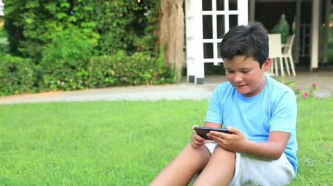 Young boy play smartphone on the grass  Stock Footage 66508533