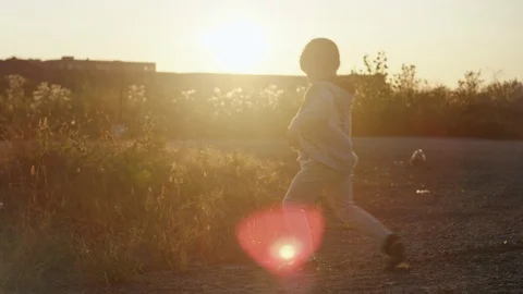 Young boy playfully kicks the pebbles on the land Stock Footage 119993191