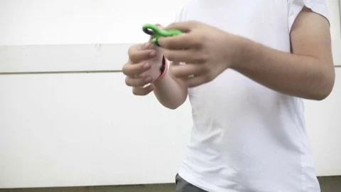 Young boy playing and making tricks with fidget spinner toy outdoor in the st Stock Footage 81429697