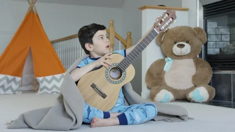 Young boy playing and tuning guitar 4K R3D Video stock 129052083