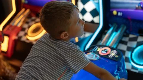 Young Boy Playing Arcade Racing Game In Entertainment Center Stock Photos