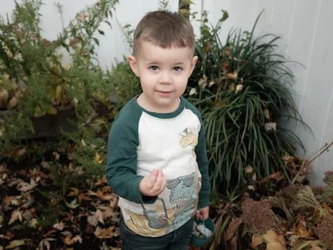 A young boy playing in the backyard on a warm day in late autumn Stock Photos