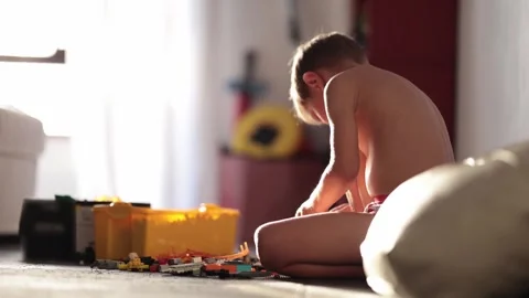 Young boy playing with building blocks on floor in sunlight Vídeos de archivo 347000727