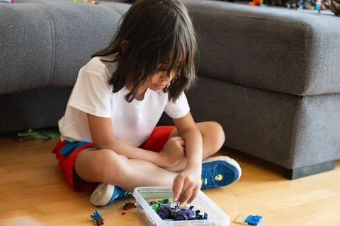 Young boy playing with building blocks, sitting on the floor in the living ro Stock Photos