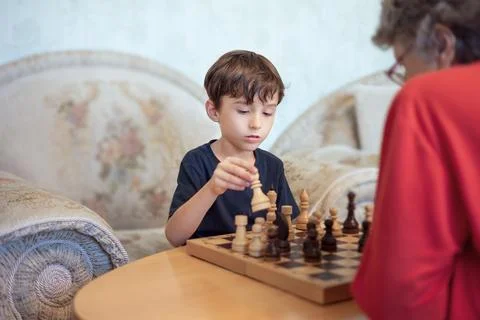Young boy playing chess with elderly woman Stock Photos