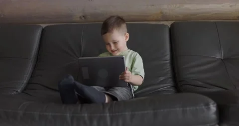 Young boy playing in a child development app on a digital tablet in a living Stock Footage 198582143