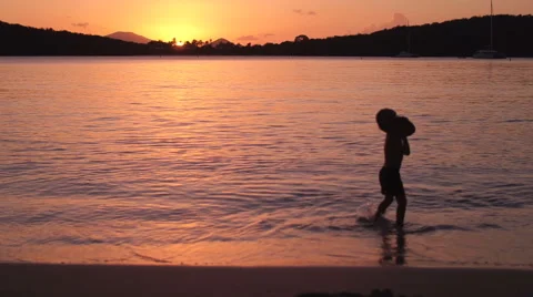 Young boy playing with coconuts at sunset on a tropical beach  Video stock 67665430