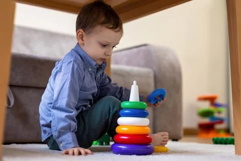 Young boy playing with colorful stacking rings. A young boy sits on the floor Stock Photos