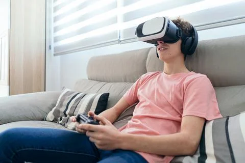 Young boy playing console with virtual reality glasses, headphones and joystick Stock Photos