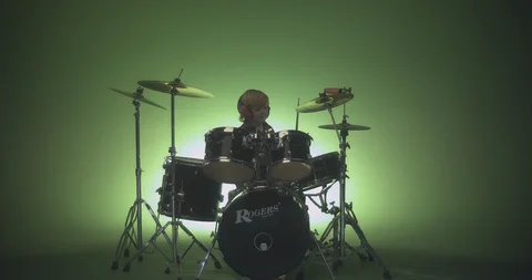 Young boy playing drum sets against green background Stock Footage 99990098