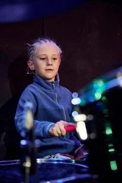 Young boy playing drums on dark stage under blue concert light Stock Photos