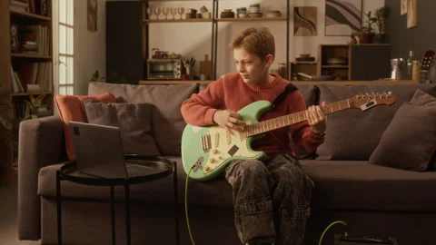Young Boy Playing Electric Guitar Following Online Lesson at Home Stock Footage 333425197