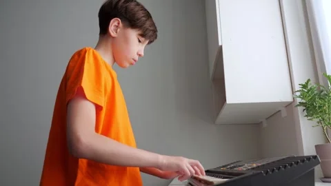 Young boy playing electronic keyboard at home Stock Footage 308434389