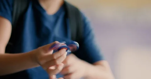 Young boy playing with a fidget spinner at school Stock Footage 108786014