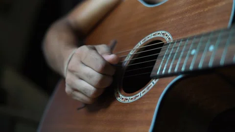 A young boy playing guitar close up with shallow depth of field. Video stock 133547568