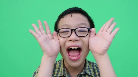 Young boy playing hide and seek in front of green screen Stock Footage 88934496