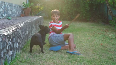 Young boy playing with his dog, french bulldog, in the garden Stock Footage 170165863