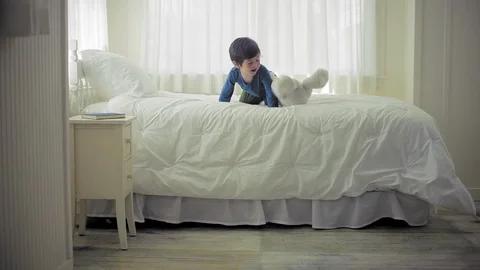 Young boy playing with his teddy bear on his bed in his bedroom. Vidéo 88341881