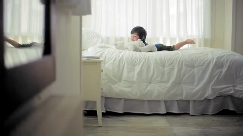 Young boy playing with his teddy bear on his bed in his bedroom. Stock Footage 88341884