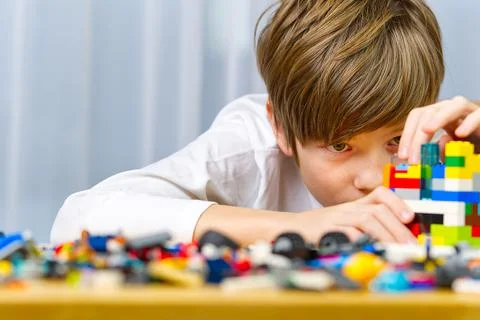Young boy playing with plastic construction toys at home. Stock Photos