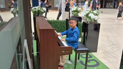Young boy playing the public piano in Glasgow Central Railway station Stock Footage 282897802