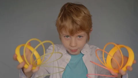 Young boy playing with rainbow colored plastic slinky toy Vídeo Stock 122257983