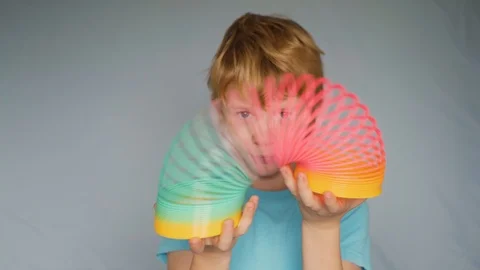 Young boy playing with rainbow colored plastic slinky toy Stock Footage 122259878